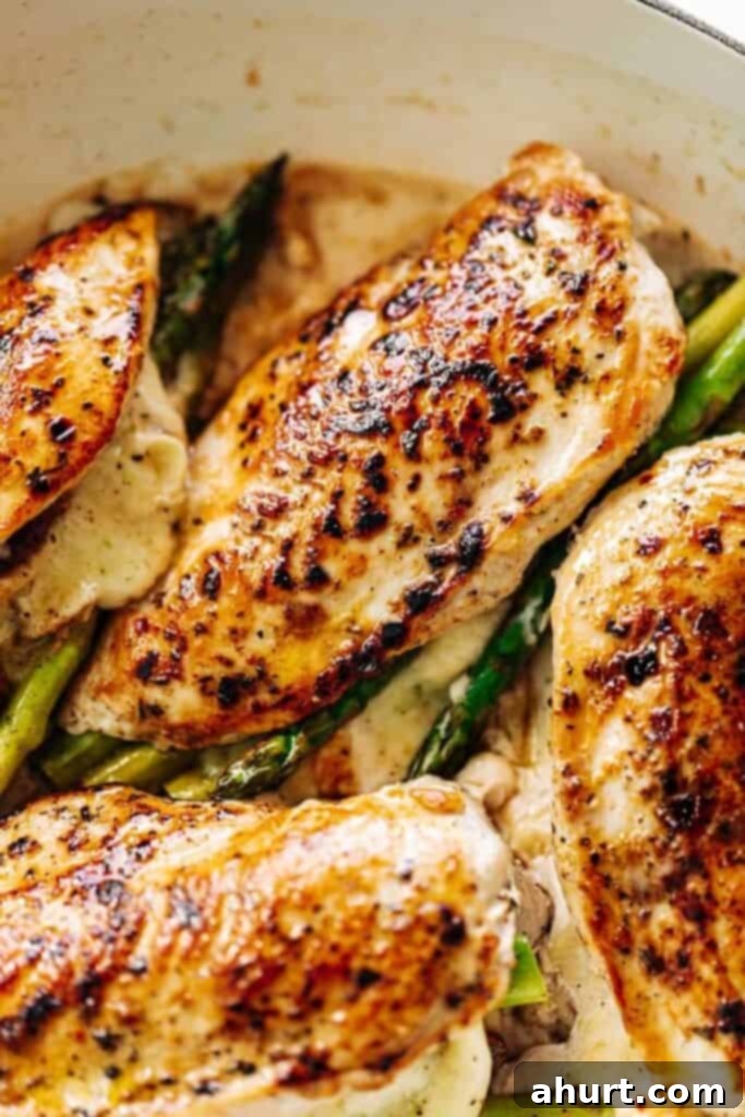 Savory Asparagus Stuffed Chicken Breasts 2 An overhead image of four asparagus and mozzarella cheese stuffed chicken breasts in a white casserole dish.