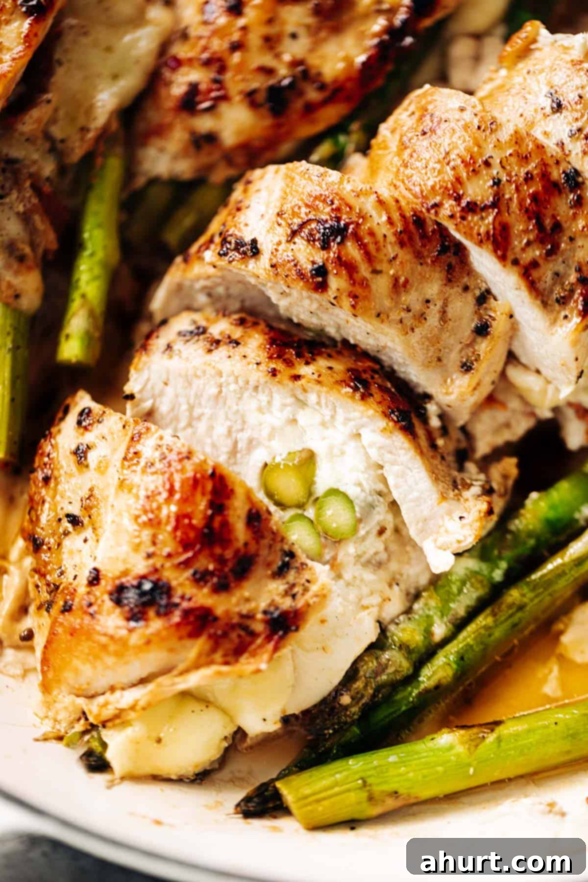 Savory Asparagus Stuffed Chicken Breasts 12 A close up image of one asparagus and mozzarella cheese stuffed in chicken breast sliced open to see the inside