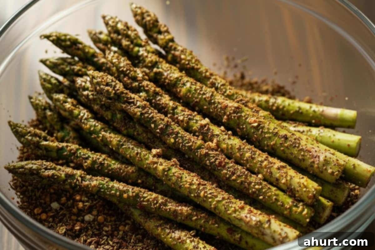 Savory Asparagus Stuffed Chicken Breasts 8 Asparagus coated with seasoning in a bowl.
