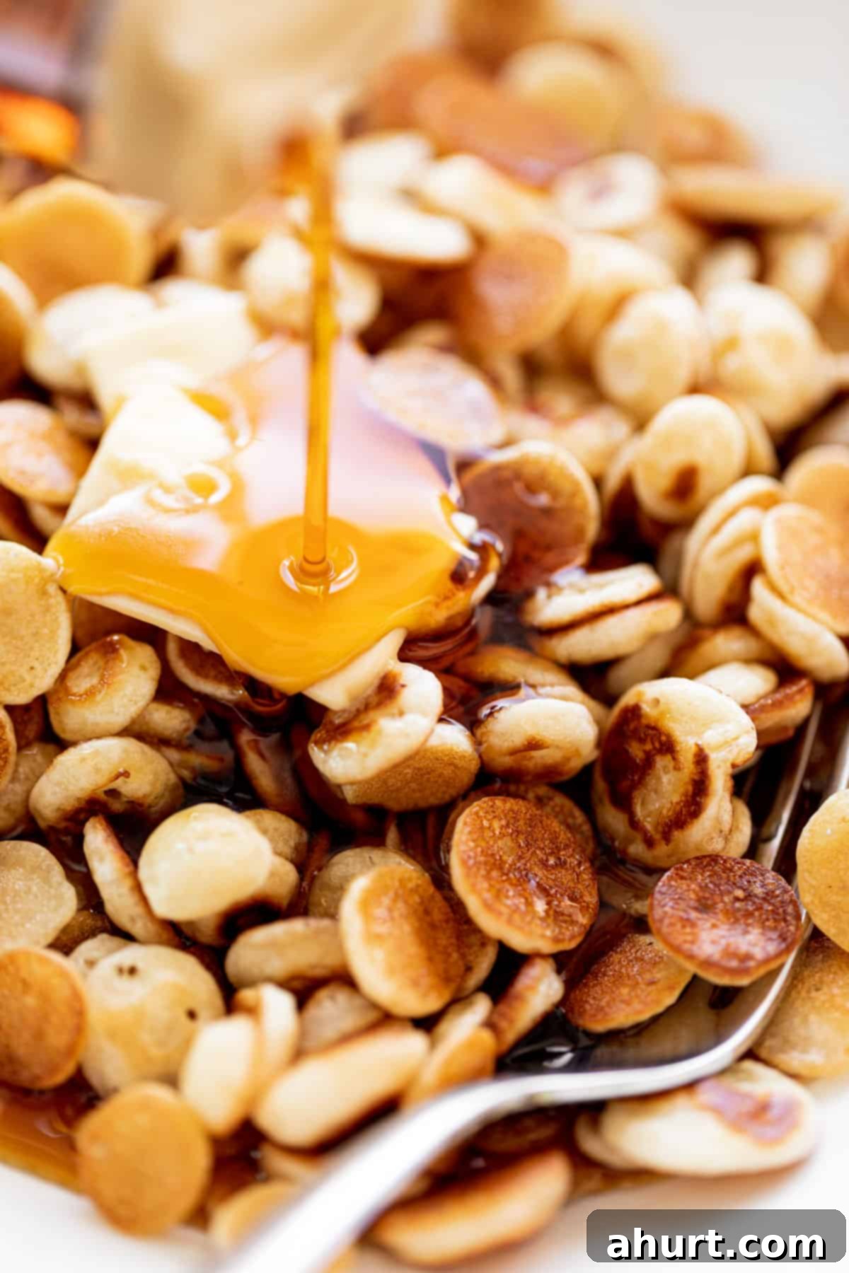 Mini Pancakes Cereal served with a piece of butter and drizzled with maple syrup.