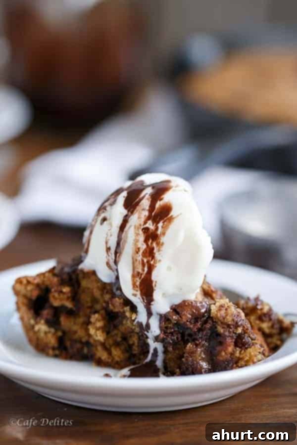 Close-up of a Peanut Butter Chocolate Chip Deep Dish Skillet Cookie slice, richly drizzled with chocolate fudge sauce.