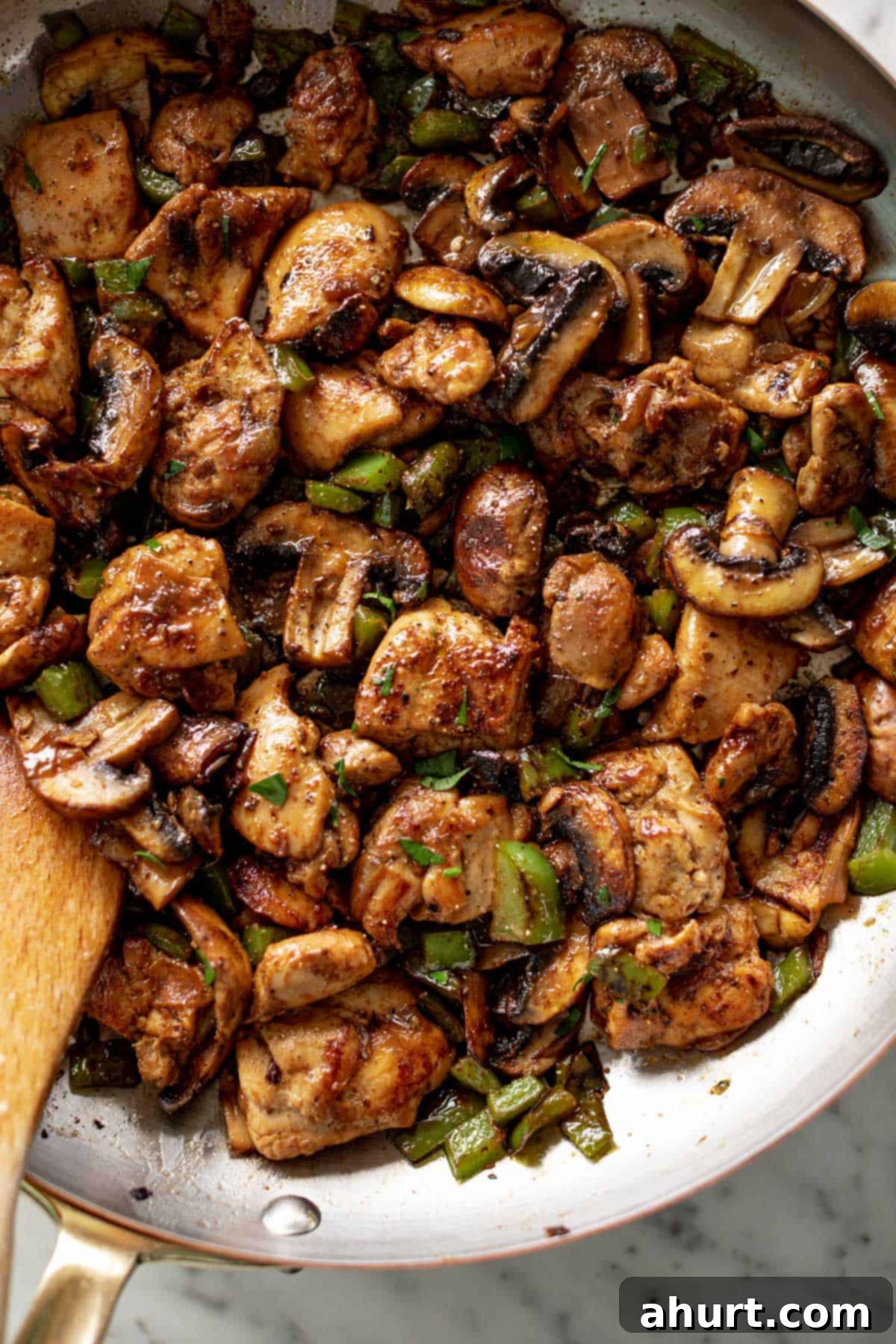 Savory Garlic Mushroom Chicken Poppers 2 garlic mushroom chicken sautéing in a pan with a wooden spoon on the side.