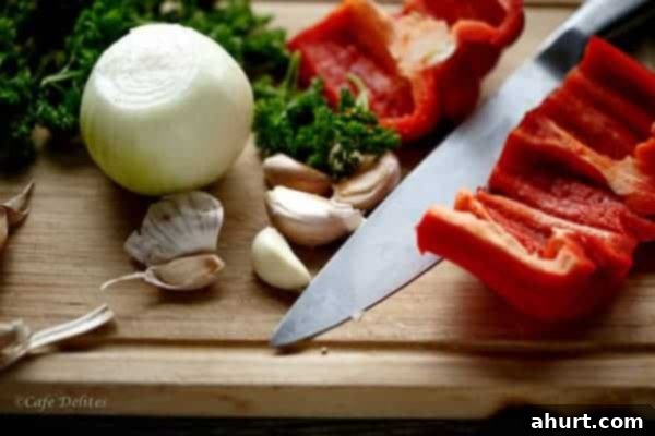 Fresh vegetables, including an onion and garlic, being expertly diced on a cutting board with a chef's knife, highlighting the start of the preparation process.
