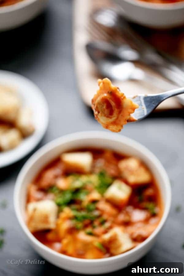 A fork lifts a piece of tender ravioli, coated in the rich creamy tomato beef sauce, from a bowl, ready to be enjoyed.