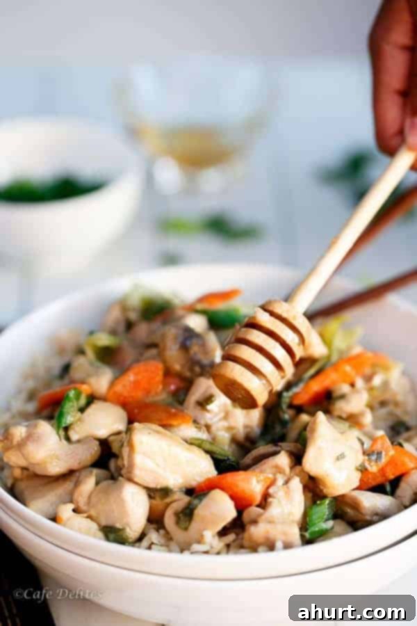 A wooden spoon scooping Honey Mustard Chicken Stir Fry from a large pot or pan