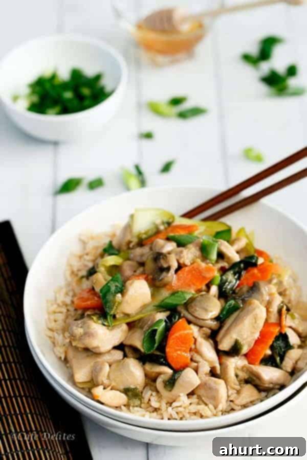 Close-up of a bowl of Honey Mustard Chicken Stir Fry with chopsticks, highlighting the texture and glistening sauce