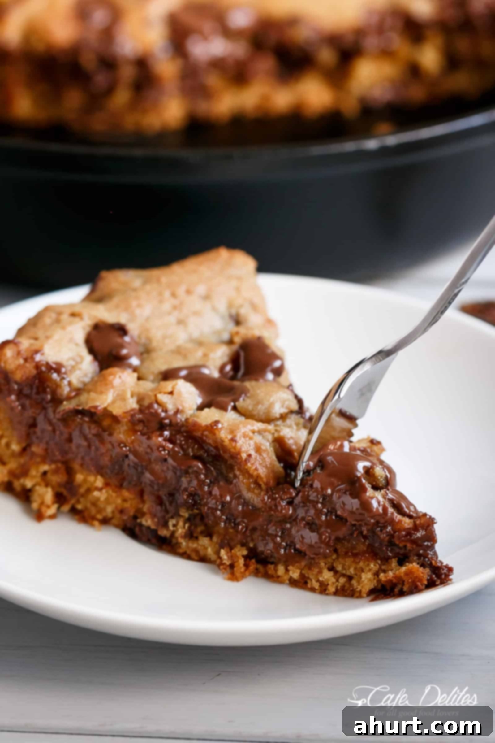 Nutella stuffed skillet cookie | cafedelites.com Nutella stuffed deep dish chocolate chip skillet cookie on a plate, with a scoop removed showing the gooey Nutella center.