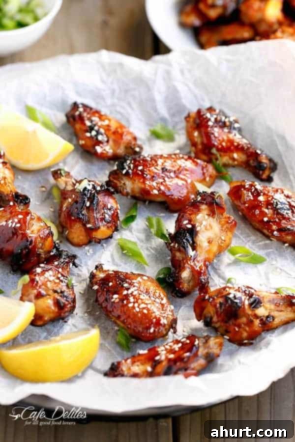 Honey Sesame Glazed Chicken 2 Sticky Honey Sesame Chicken Wings with lemon wedges on a baking tray