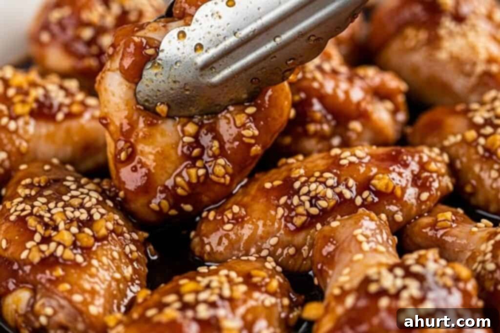 Honey Sesame Glazed Chicken 5 Chicken wings marinating in a shallow dish with sauce.