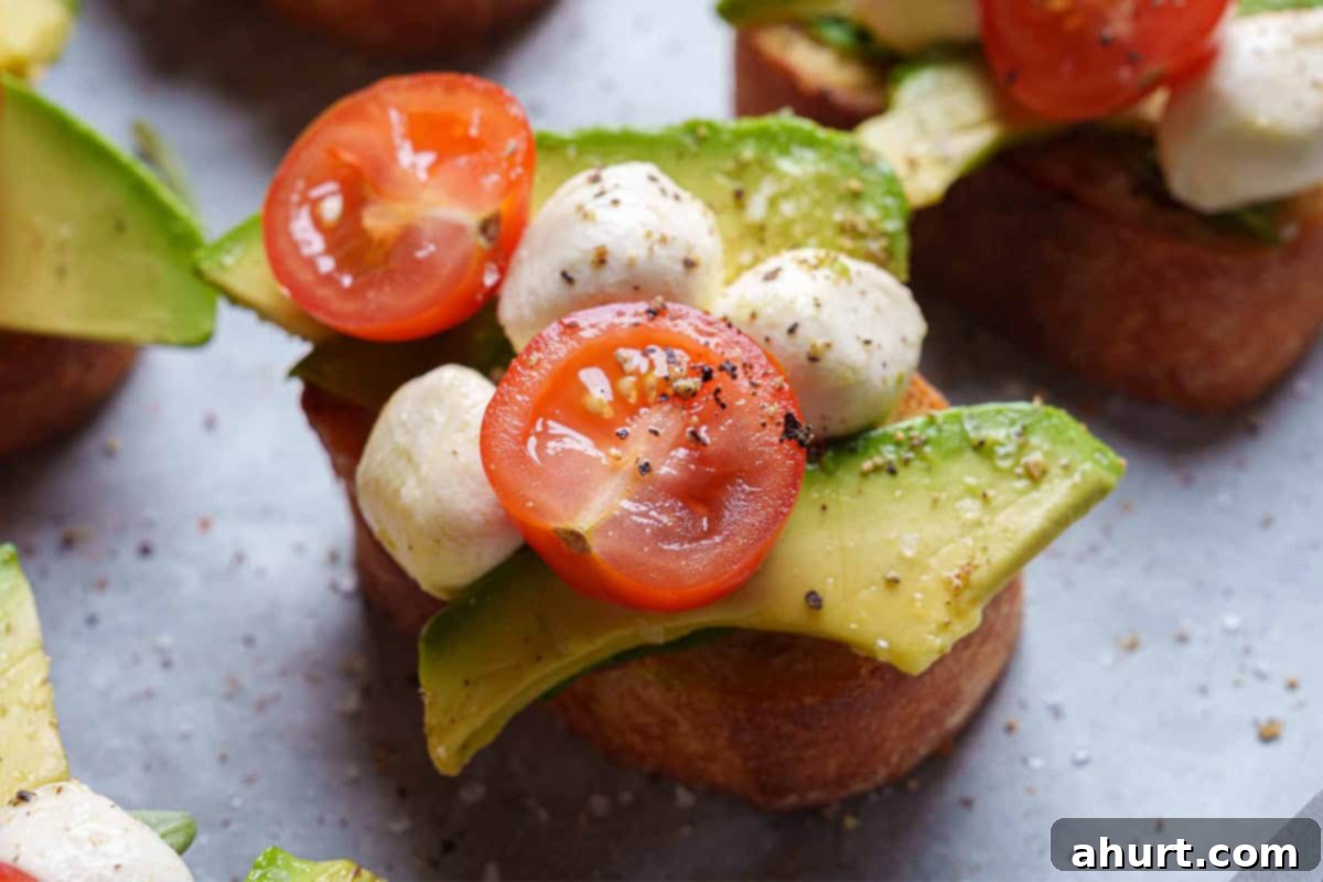 Zesty Caprese Crostini with Smoky Grilled Avocado 7 basil leaves and other toppings placed on each slice