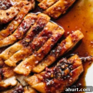 Fiery Honey Glazed Chicken 9 Chicken breast with hot honey butter sauce on a white plate.