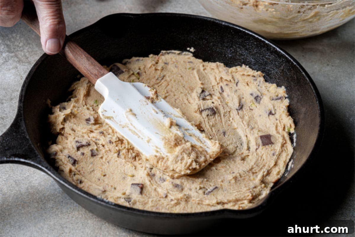 Pistachio Chocolate Chip Skillet Cookie 8 Step 5: Spread half of the prepared cookie dough evenly onto the parchment-lined skillet, forming the base layer.