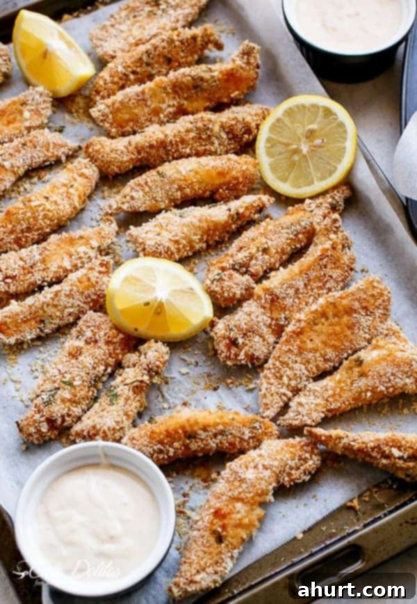 Garlic Chicken Strips on a baking tray with lemon wedges and Chili mayo dip in bowl