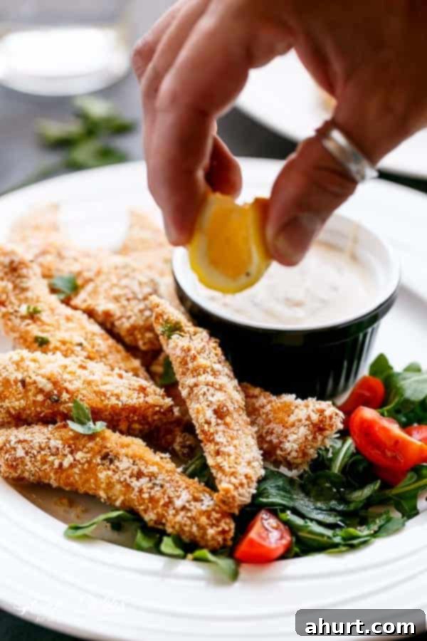 Lemon being squeezed over Garlic Chicken Strips 