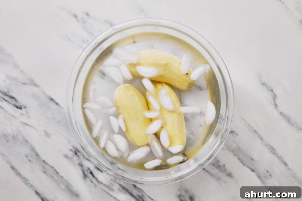 Golden Crispy Fries 4 peeled potatoes in a bowl with ice and water