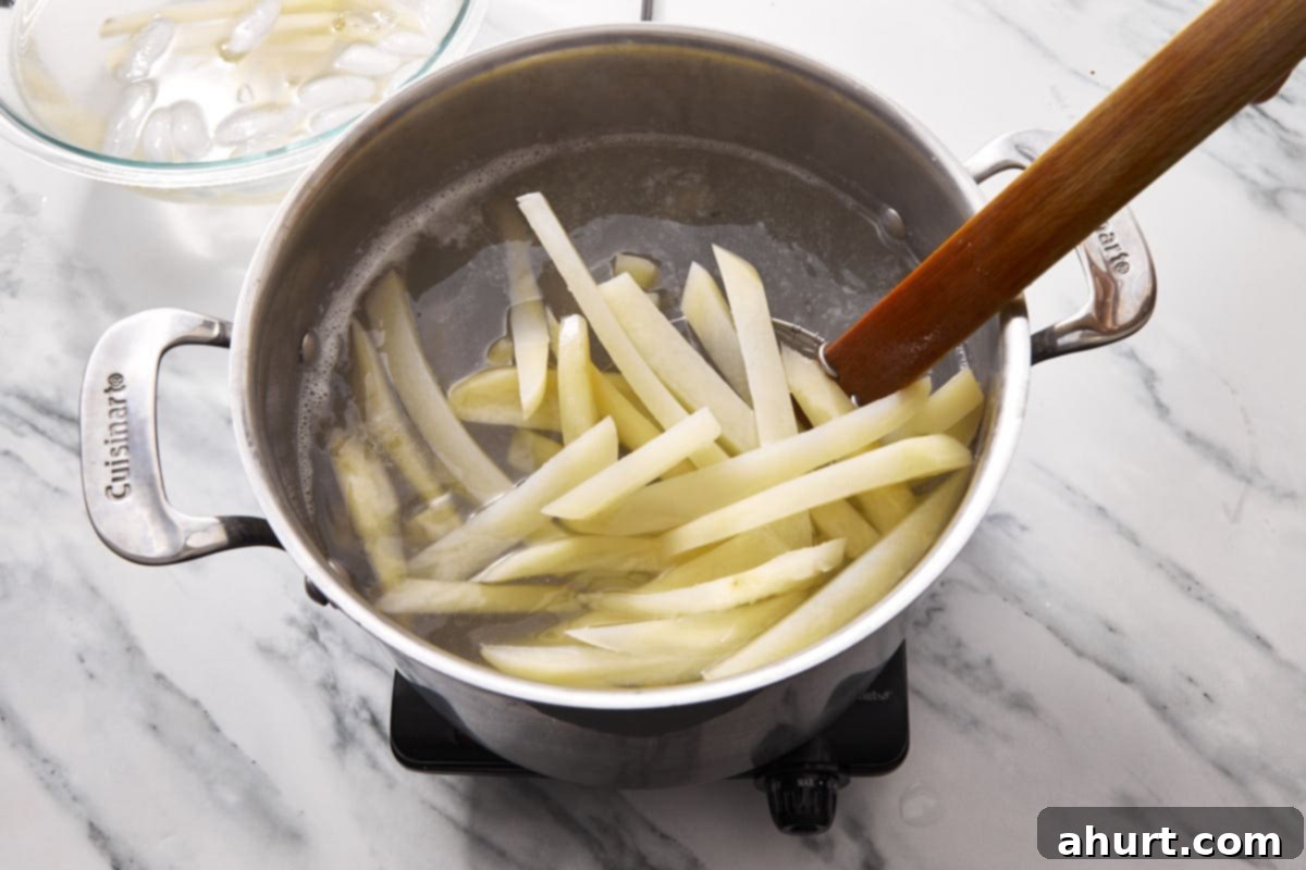 Golden Crispy Fries 5 chopped potatoe fries uncooked in a pot being boiled