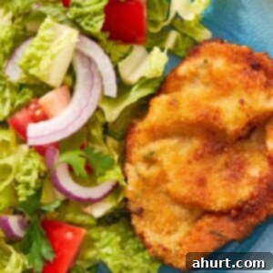 The Ultimate Beef Milanesa Experience 11 Crispy beef milanesa served with fresh tomato salad and greens on a white plate