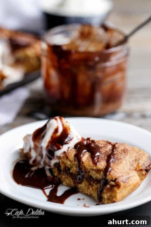 A perfectly plated slice of Nutella Stuffed Churro Deep Dish Skillet Cookie with ice cream and sauce, ready to be enjoyed
