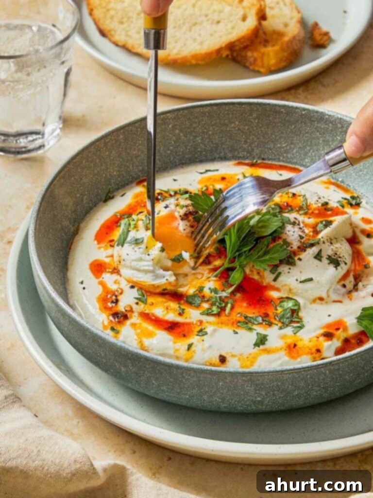 Cilbir Turkish Eggs 2 Cutting into a soft poached egg over creamy yogurt and chili butter — golden yolk, meet toasted bread.