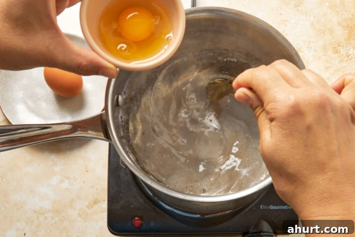 Cilbir Turkish Eggs 6 Preparing poached eggs by cracking one into simmering water.