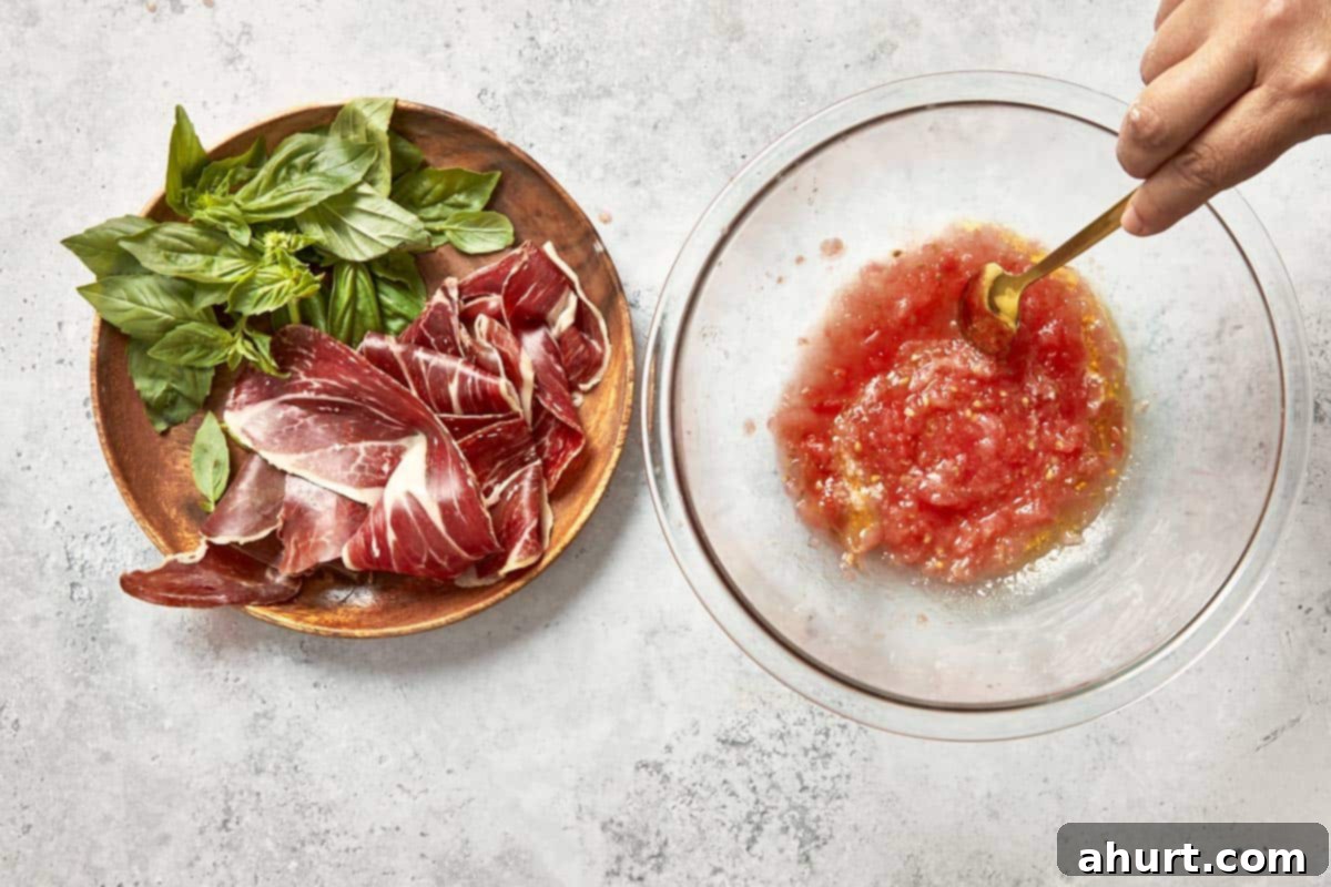 Spanish Tomato Pan Coca 13 Spanish tomato topping being stirred in a bowl with Jamón Ibérico and fresh basil on the side.