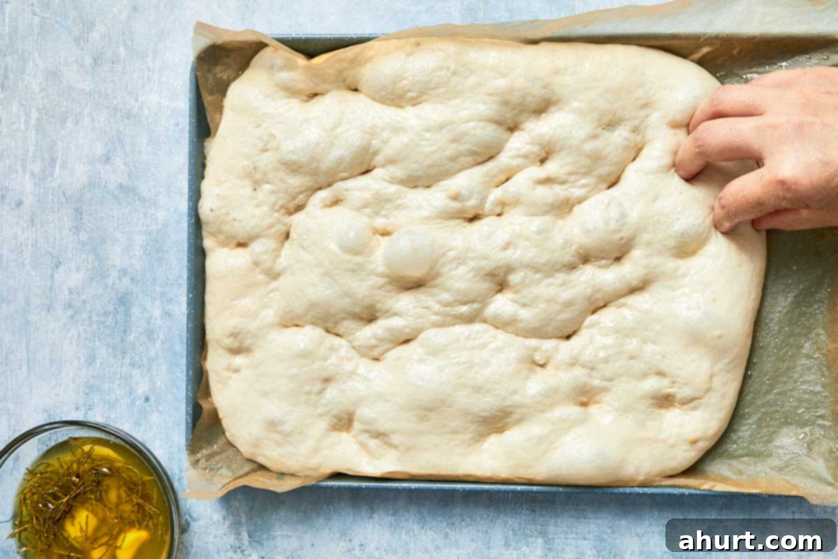 Effortless Homemade Focaccia 15 Fingers pressing dimples all over the surface of the rested dough, creating signature texture.