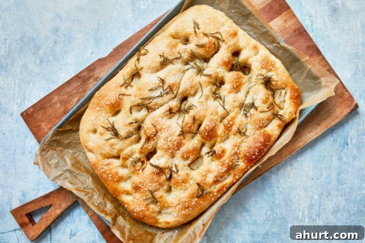 Effortless Homemade Focaccia 17 Golden-brown baked focaccia fresh out of the oven, topped with fresh rosemary sprigs.