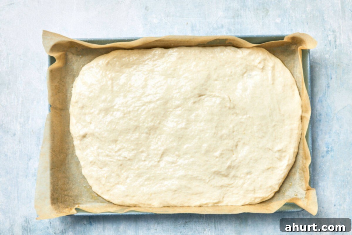 Effortless Homemade Focaccia 10 Dough spread fully in the baking pan, ready to begin its first rise.