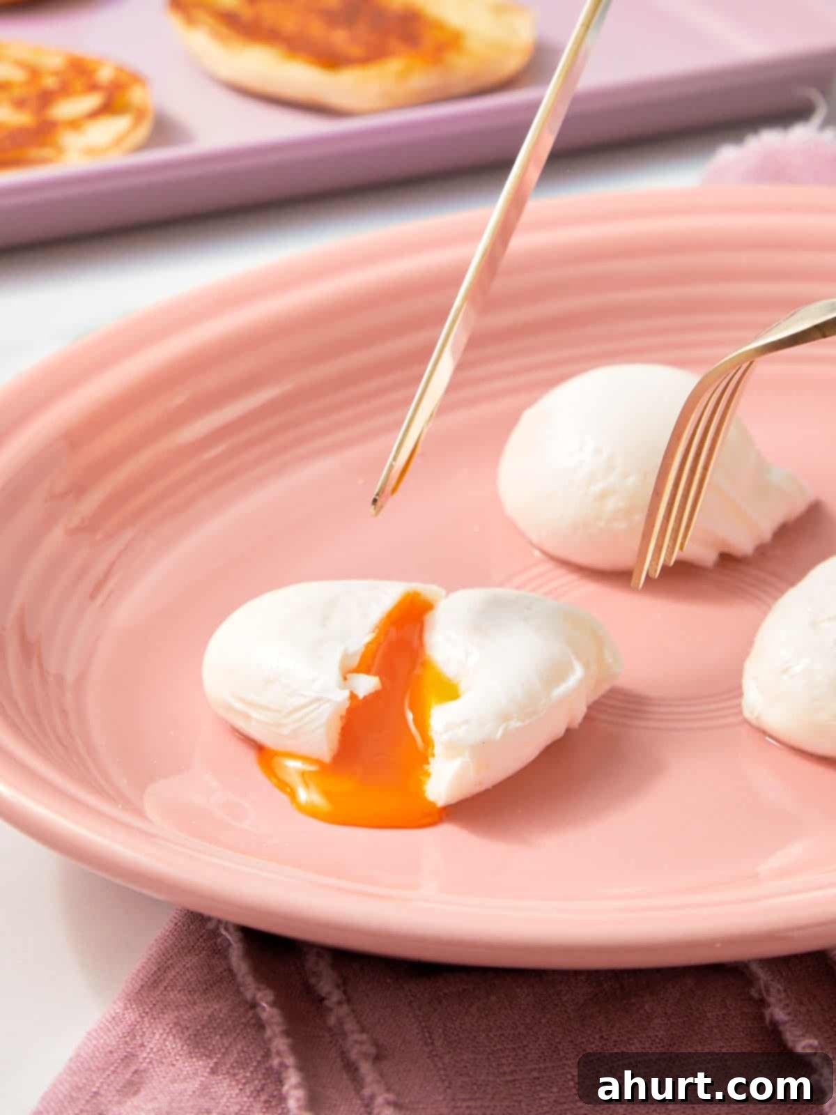 Mastering Perfect Poached Eggs 2 Three poached eggs on a plate, with a fork and knife cutting into one — the golden yolk spilling out softly.