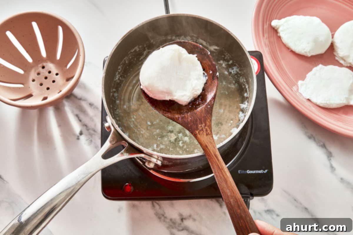 Mastering Perfect Poached Eggs 5 A poached egg being lifted from hot water with a slotted spoon, surrounded by perfectly cooked eggs on a plate.