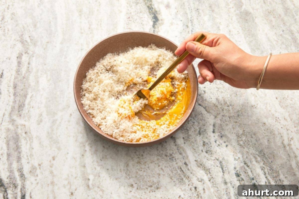 Velvet Carbonara Bliss 6 Grated Pecorino Romano being mixed with egg yolks and black pepper.