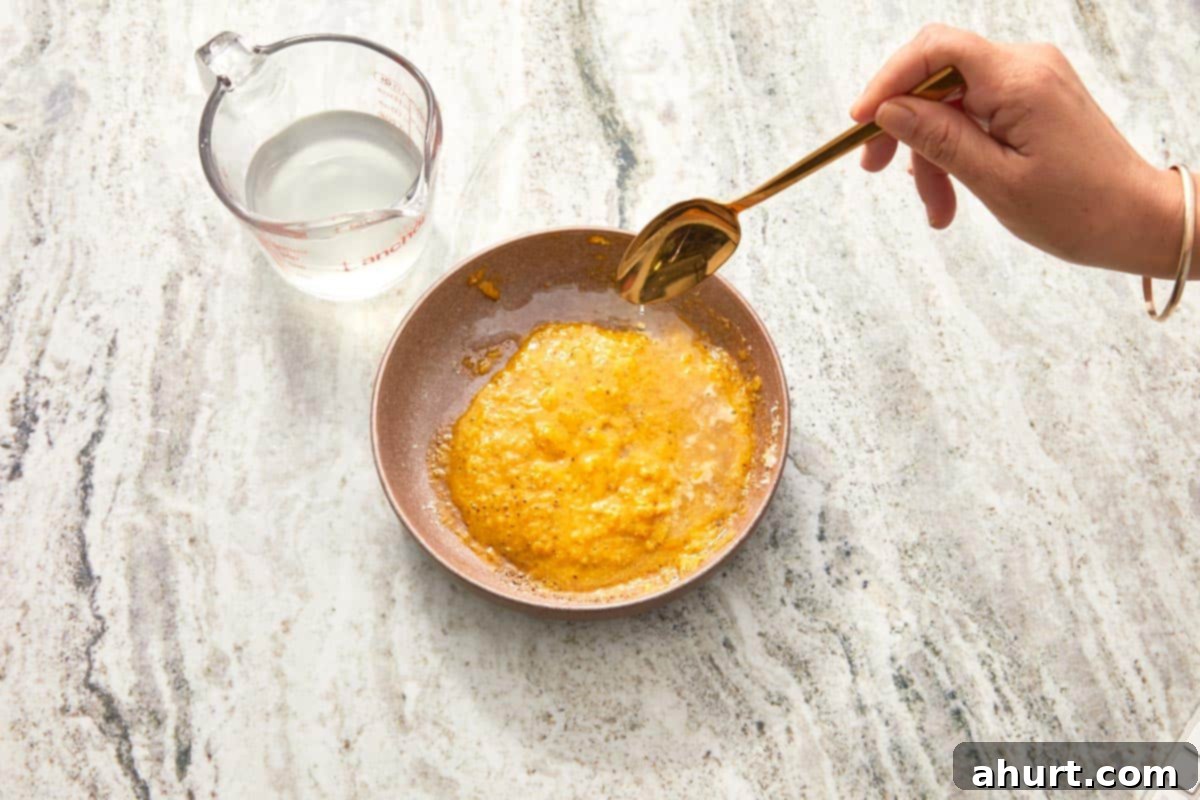 Velvet Carbonara Bliss 7 Hot pasta water being whisked into the yolk and cheese mixture.