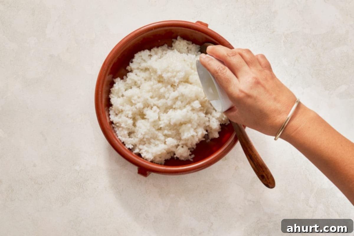 Easy At-Home Sushi Bake 4 Hand grips a spoon poised over a bowl of rice