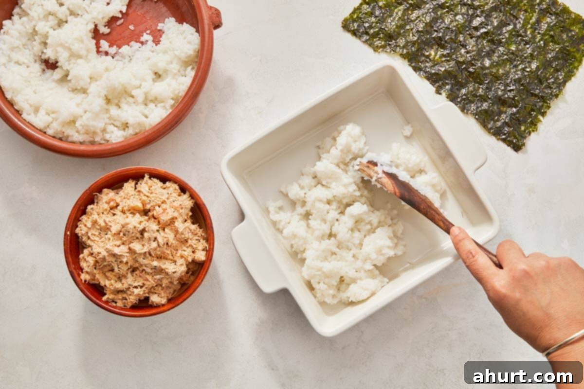 Easy At-Home Sushi Bake 7 Stirring rice into a bowl with a spoon, layering it
