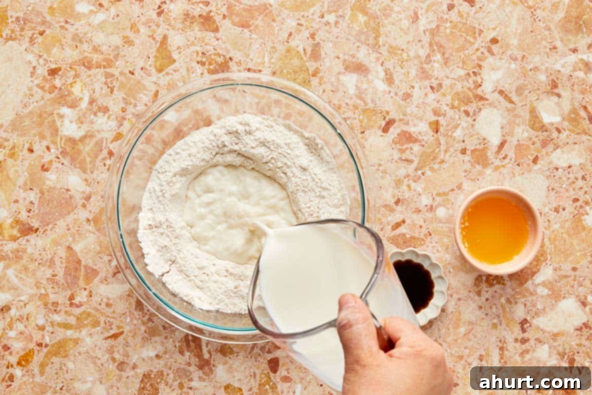 The Ultimate Paffles Waffle Pancake Perfection 5 Pouring flour into a bowl with other wet ingredients, preparing to whisk the mixture into a smooth batter.