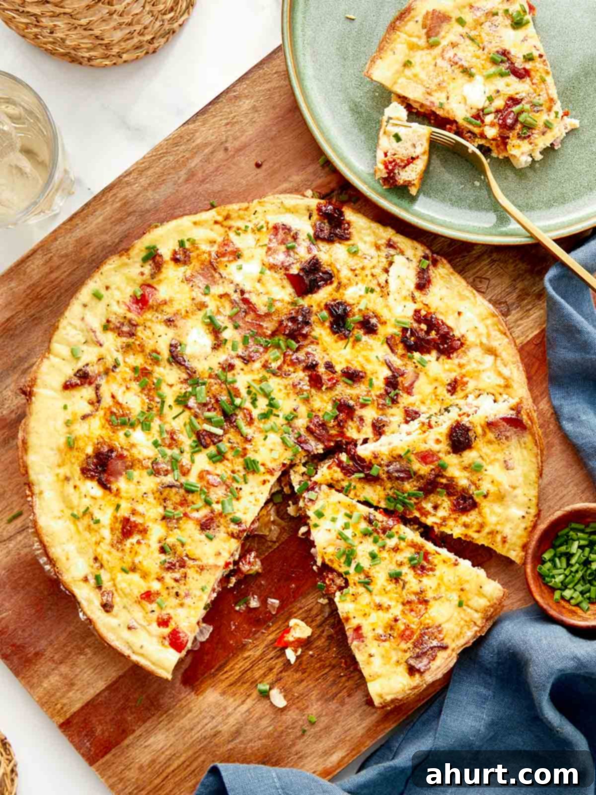Frittata The Brunch Showstopper 2 A beautifully cooked whole frittata on a rustic wooden board, golden and slightly puffed, generously topped with crispy bacon pieces and fresh green chives. Serving plates, forks, and knives are artfully arranged around it, inviting guests to enjoy.