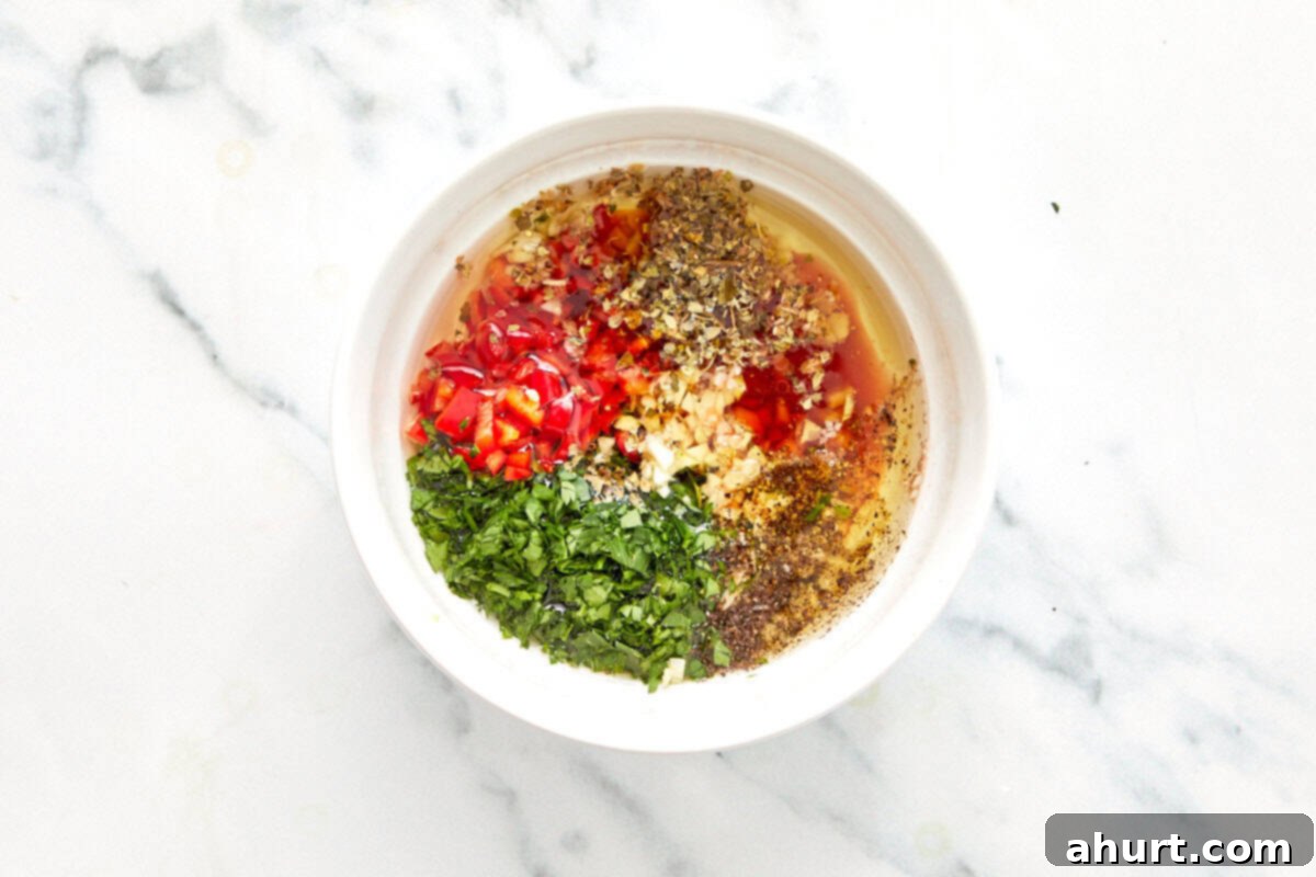 Sizzling Lobster Tails with Herbaceous Chimichurri 4 Bowl with chopped parsley, garlic, red chili, oregano, and black pepper ready to be mixed with olive oil and vinegar for chimichurri.