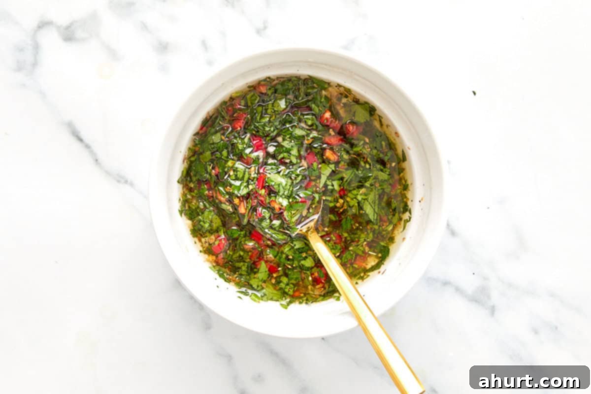 Sizzling Lobster Tails with Herbaceous Chimichurri 5 Chimichurri sauce fully mixed in a white bowl with visible herbs and chili, ready to rest.
