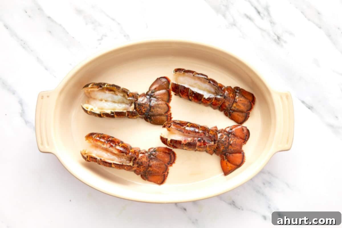 Sizzling Lobster Tails with Herbaceous Chimichurri 6 Raw lobster tails sliced open and arranged in an oven-safe baking dish, ready for seasoning.