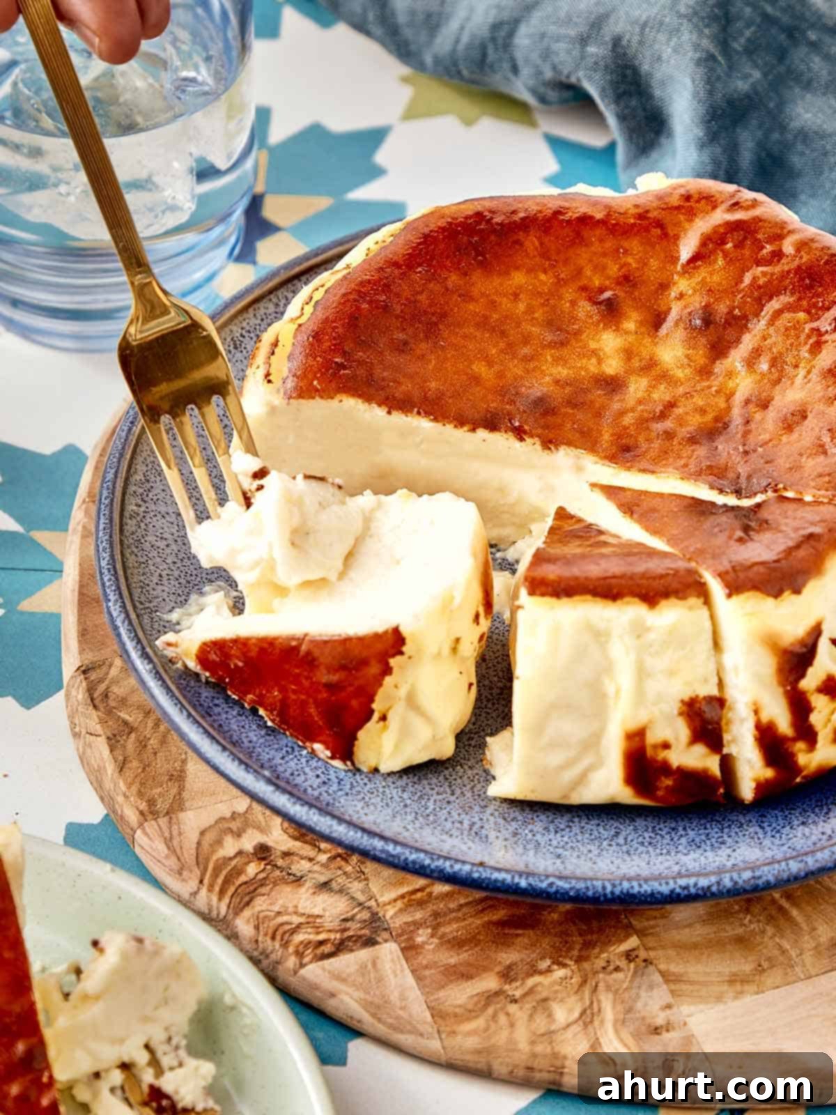 Burnt Basque Cheesecake 2 Basque cheesecake slice being cut with a fork on a blue plate, highlighting its creamy texture