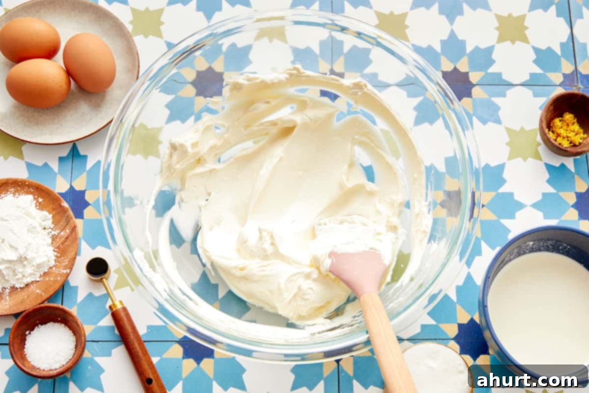 Burnt Basque Cheesecake 4 Cream cheese whipped smooth in a glass bowl with baking ingredients around it
