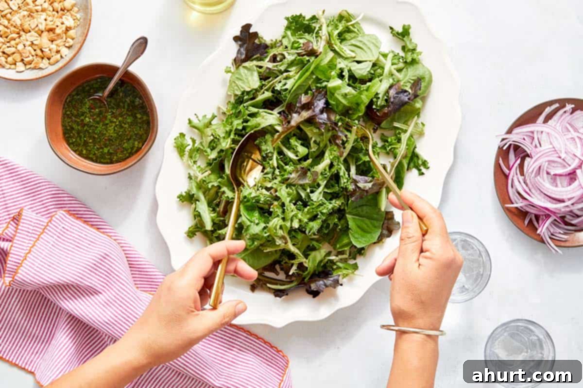 Vibrant Thai Beef Salad 12 Mixed greens being tossed with dressing in a large platter, preparing for the steak.