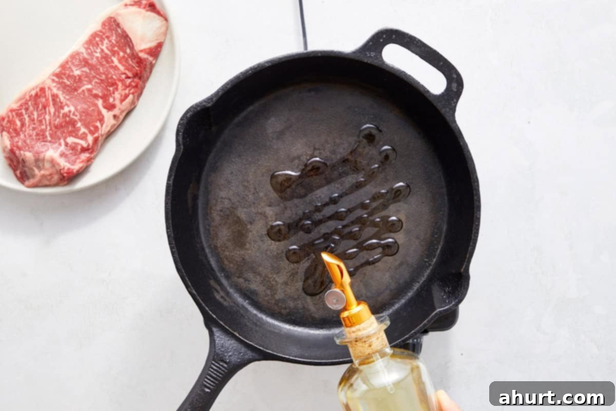 Vibrant Thai Beef Salad 6 An oiled cast-iron skillet on a burner, with steak resting beside it, ready for searing.