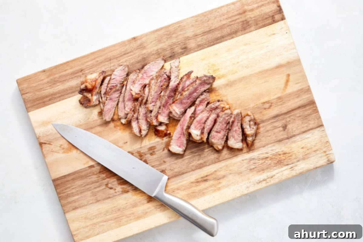 Vibrant Thai Beef Salad 10 Steak sliced thinly against the grain on a cutting board, ready for the salad.