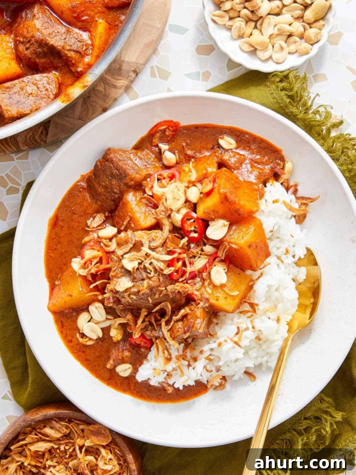 Rich Massaman Beef Curry 2 Massaman Beef Curry served over jasmine rice, topped with roasted peanuts and crispy shallots, ready to be enjoyed.
