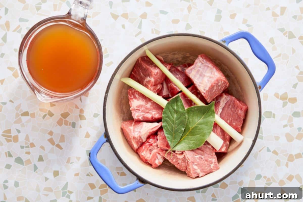 Rich Massaman Beef Curry 4 Beef chunks simmering with lemongrass and bay leaves in a pot with beef broth.