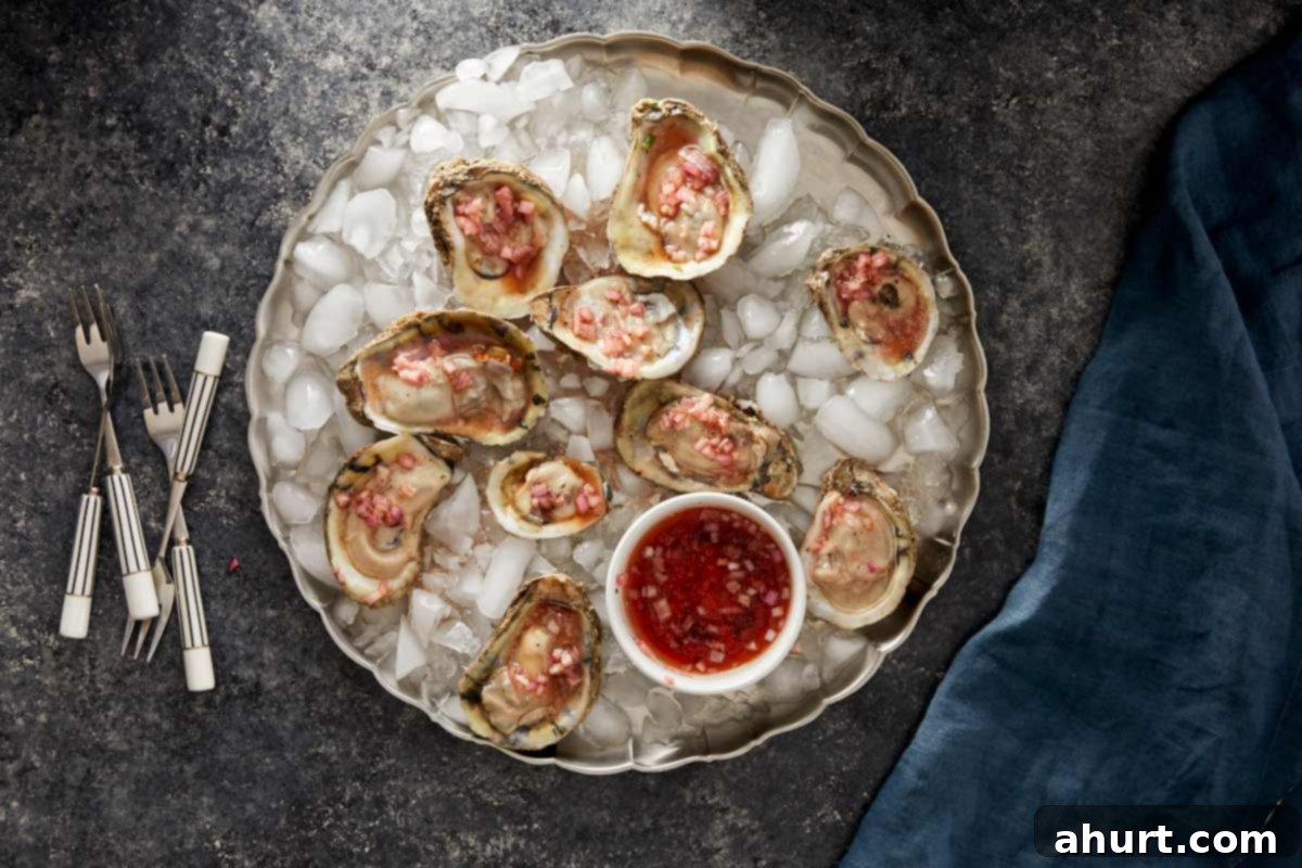 Oysters on ice topped with shallot vinegar mignonette and a small bowl of sauce in the center.