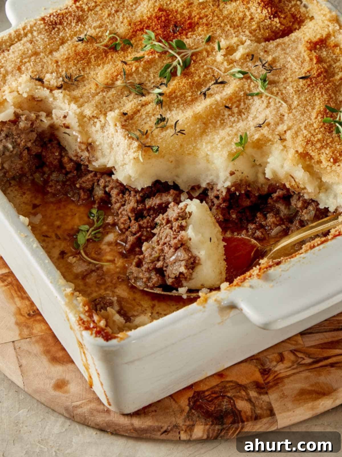 Slice of Shepherd’s Pie with golden mashed potato topping on a plate, garnished with fresh herbs, ready to be enjoyed.