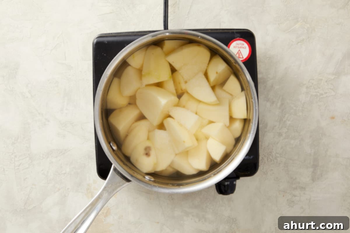 Peeled potato chunks boiling in salted water, preparing them to be mashed into a creamy topping for the Shepherd's Pie.
