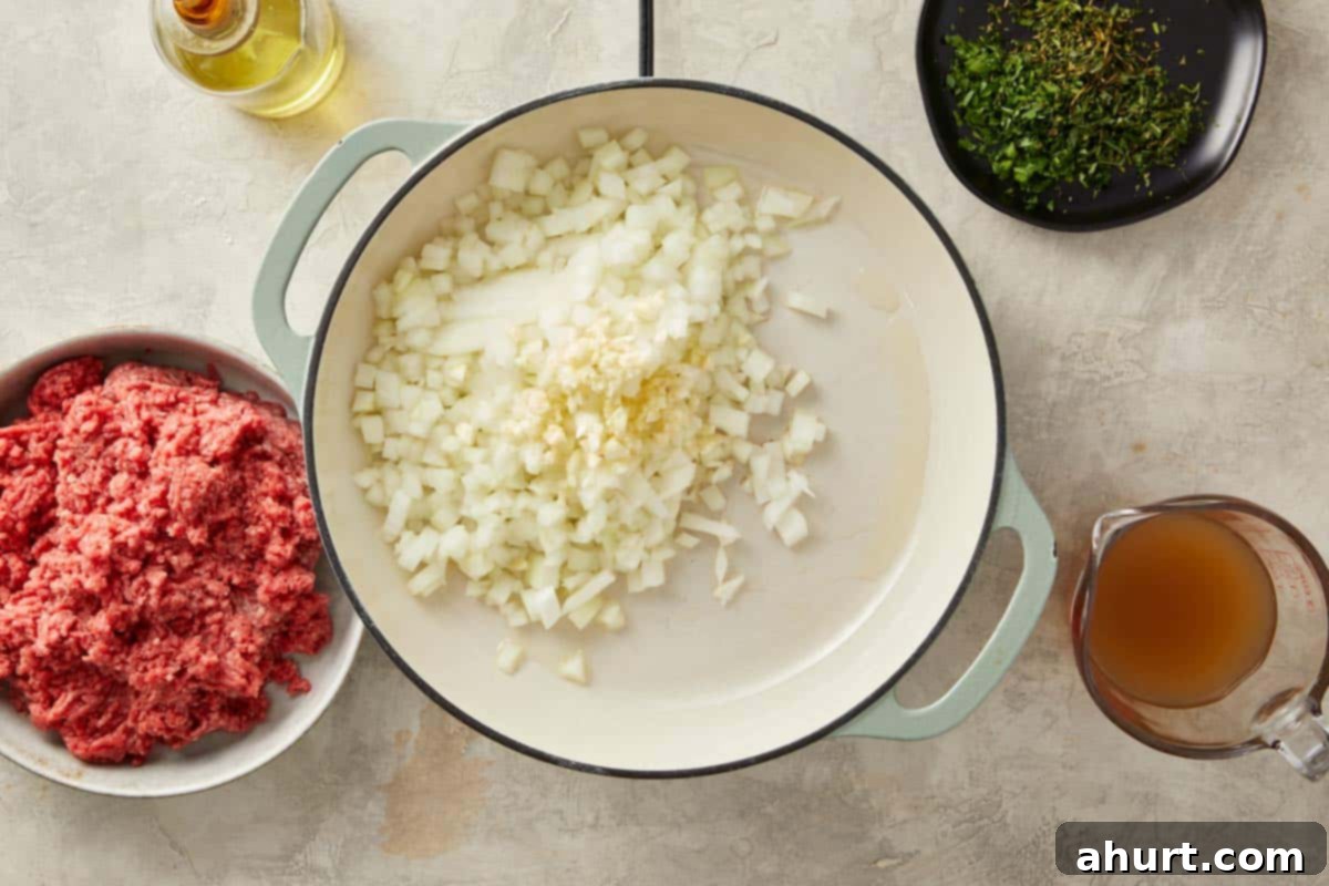 Finely chopped onions and minced garlic gently sautéing in a pan with olive oil and butter, releasing their sweet and savory aromas.
